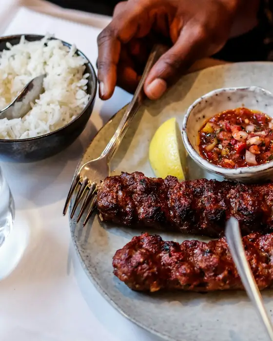Kebabs served with grilled tomato, peppers and rice